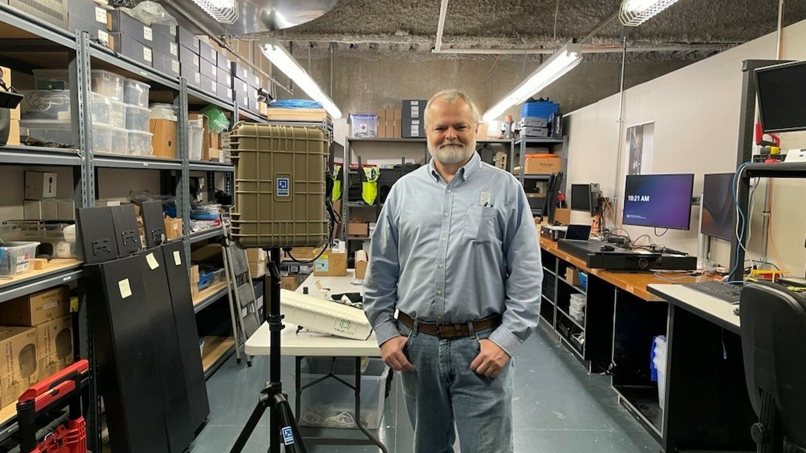 Steve Tyng stands in front of a custom hotspot and other network equipment.