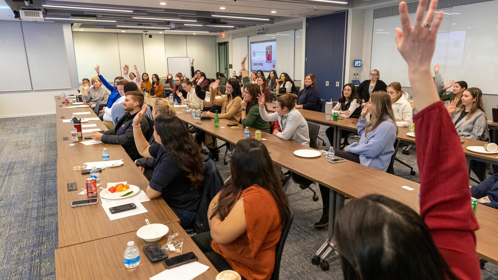 An audience raises their hands at an event discussing the advancing role of women in construction