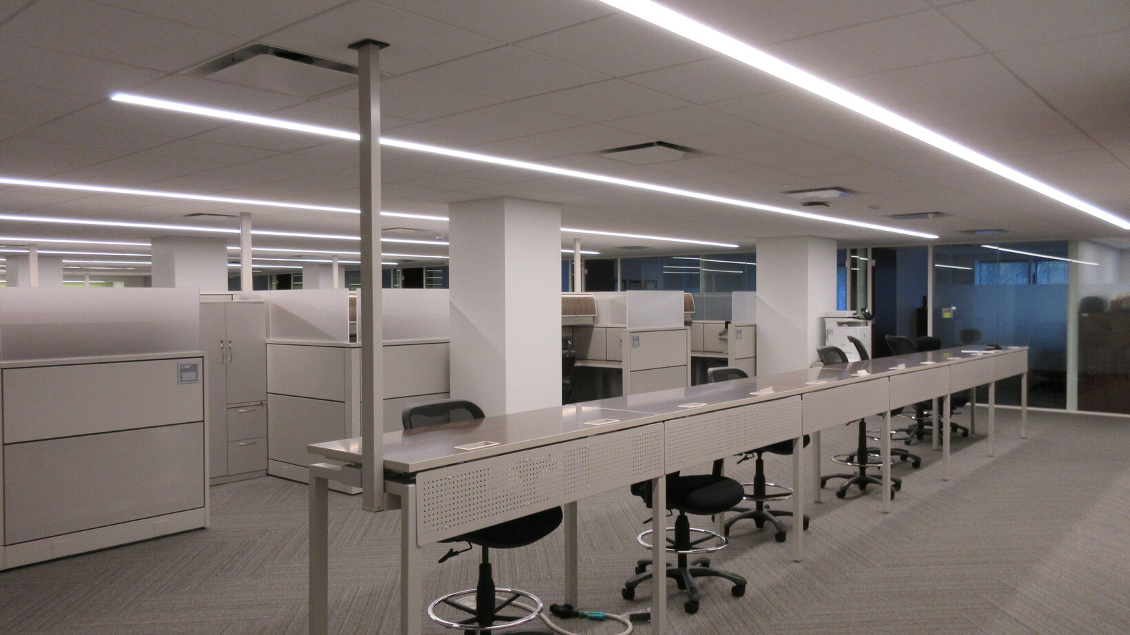 Open work space with desks and chairs, and an overhead fluorescent light