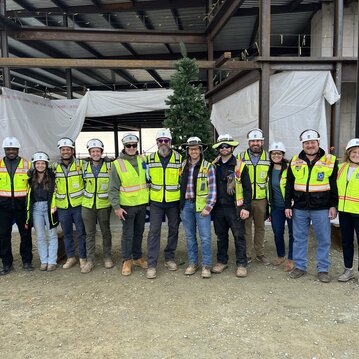 A group of construction workers poses in front of the last beam at a topping out celebration.