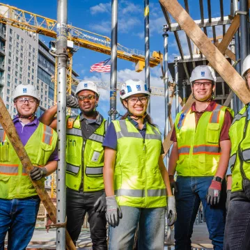 A group of construction workers pose at a construction site.