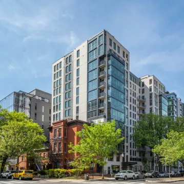 Exterior shot of an apartment building in the day. Trees are around.