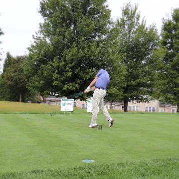 A man swings a golf club on a golf course
