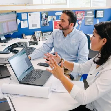 two white adults looking at computer monitor