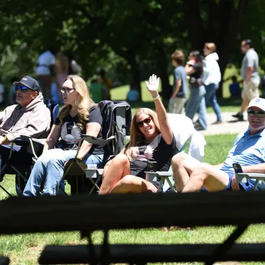 woman waving at camera during outdoor picnic