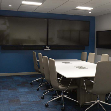 A conference room complete with a flatscreen TV, a long table and chairs.