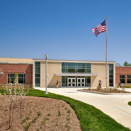 A school with a courtyard in front and an American flag on its roof.