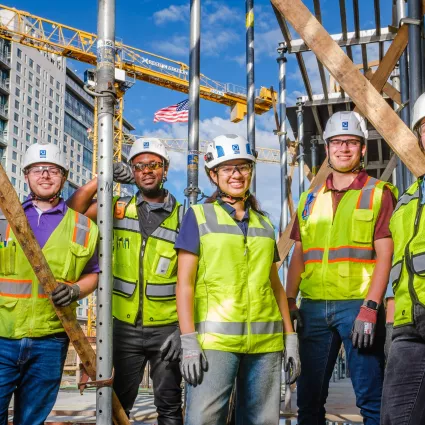 A group of construction workers pose at a construction site.
