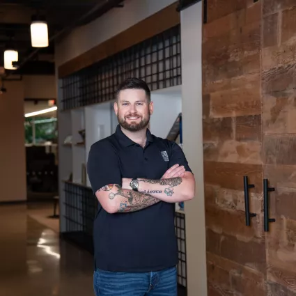 A man in professional wear stands in a hallway.