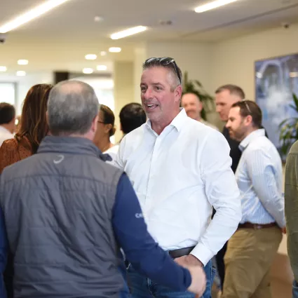 Groups of people gather in a hallway and network during the trade partner symposium