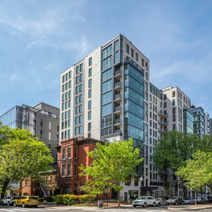 Exterior shot of an apartment building in the day. Trees are around.