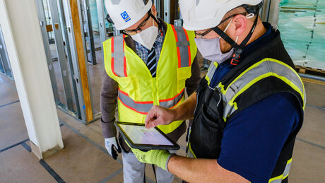 DAVIS Employees wearing safety gear look at a tablet