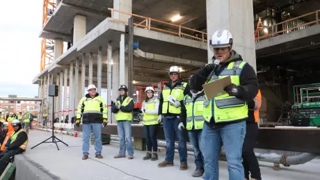 DAVIS employees stand in front of a crowd of trade partners and workers. One employee holds a mic and speaks about mental health.