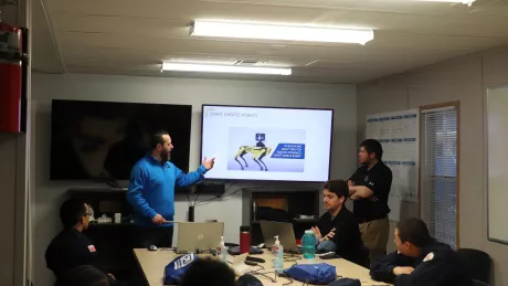 A man stands in front of students presenting on virtual construction.
