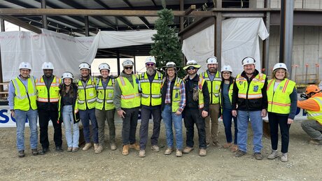 A group of construction workers poses in front of the last beam at a topping out celebration.