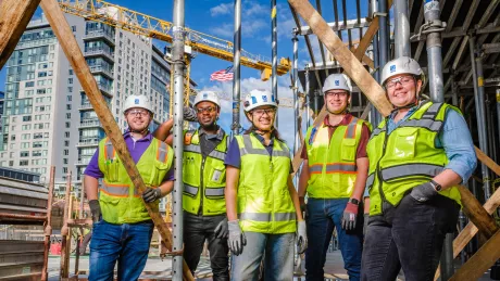 A group of construction workers pose at a construction site.