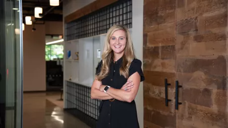 A woman in professional wear standing in an office hallway