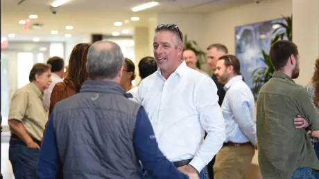 Groups of people gather in a hallway and network during the trade partner symposium