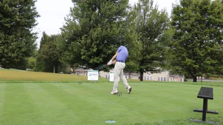 A man swings a golf club on a golf course