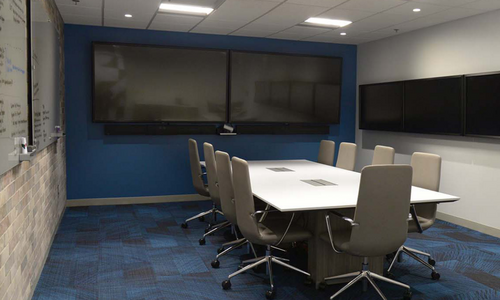 A conference room complete with a flatscreen TV, a long table and chairs.