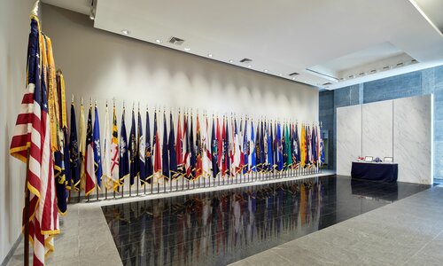The front desk at the Military Women's Memorial has many flags flags on display, from the American flag to individual states.
