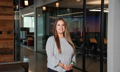 A woman in professional wear standing in an office hallway