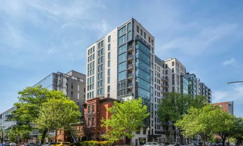 Exterior shot of an apartment building in the day. Trees are around.