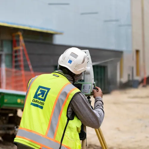 DAVIS employee looking through construction surveyor