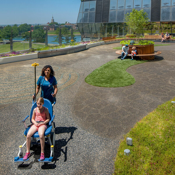Girl in wheelchair being pushed by a medical professional in the healing garden
