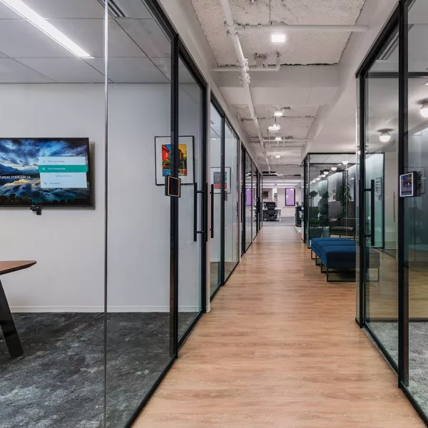 hallway with glass enclosed meeting rooms off the sides