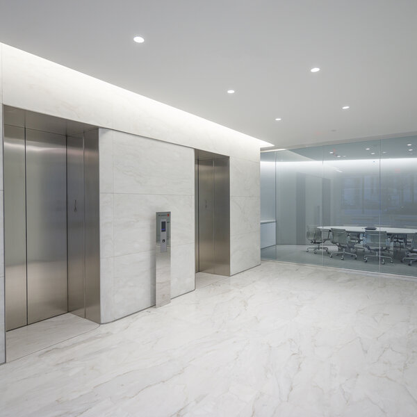 An elevator bay with marble floors.