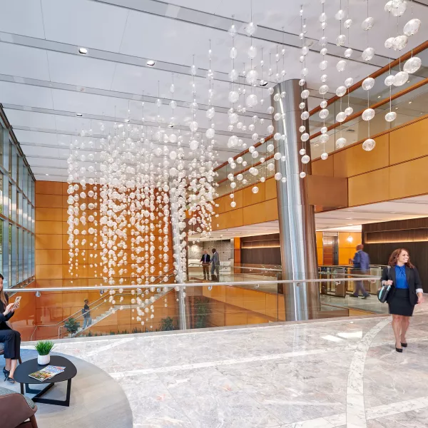 A man and woman near a grand stairway, near fancy light fixtures.