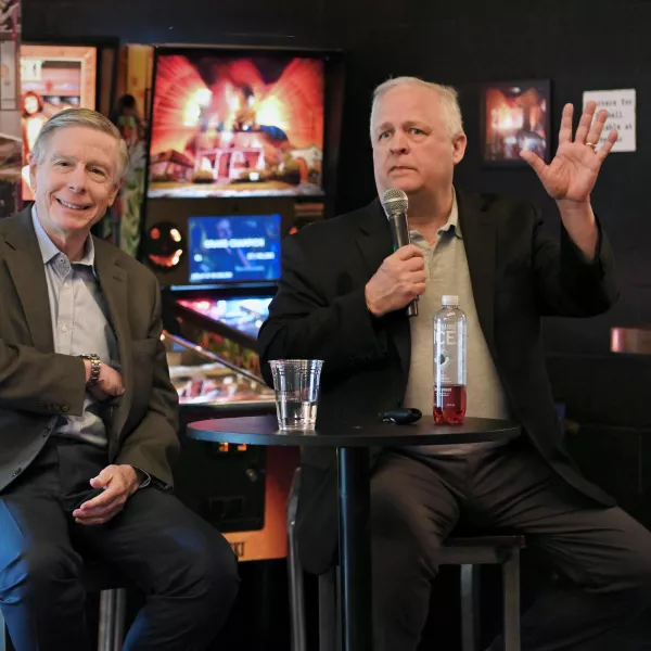 Speakers at an event sit in chairs.