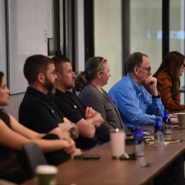 People sit behind a long desk and listen to a presentation