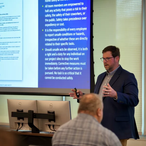 Man stands at the front of a room giving a presentation