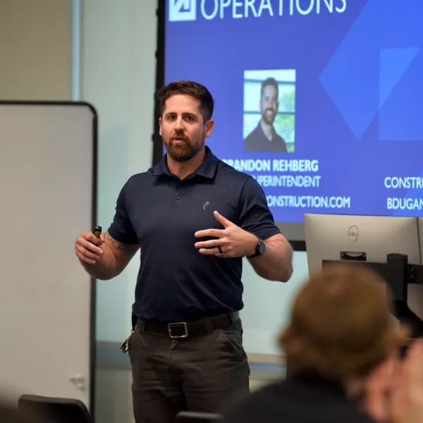 Man stands at the front of a room giving a presentation