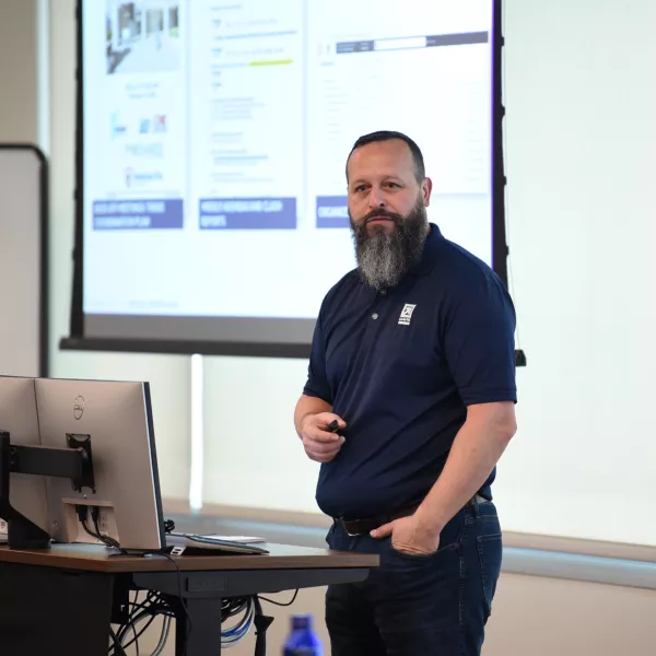 Man stands at the front of a room giving a presnetation