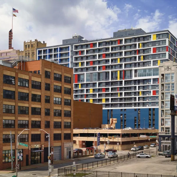 Exterior shot of an apartment building behind other buildings.