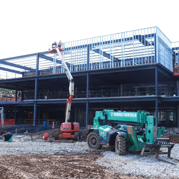 Ongoing three-story construction site with work vehicles in front