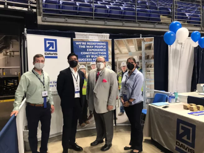 Four professionally dressed people in a convention booth looking at camera