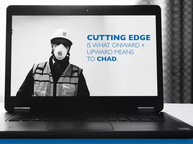 Chad Oursler image on computer screen. Chad is wearing goggles, hardhat, construction vest and mask