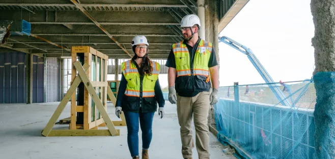 A man and a woman walk together on a construction site